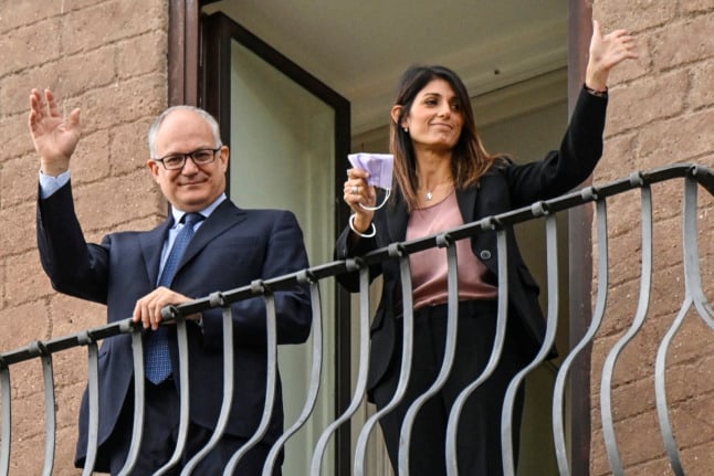 Gualtieri and outgoing Rome mayor Virginia Raggi wave from a balcony during a handover ceremony on October 21, 2021. 