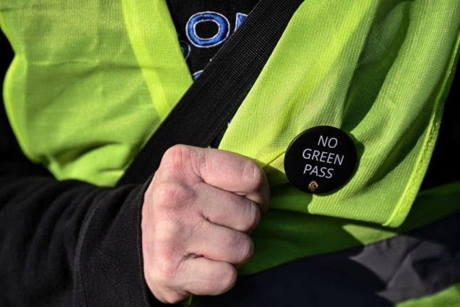 A docker wears a "No Green Pass" pin as workers block port operations in the port of Genoa, Liguria, on October 15, 2021 as new coronavirus restrictions for workers come into effect.