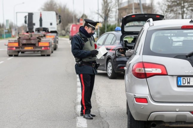 A Carabinieri police officer checks a driver's papers at a road check point on March 9, 2020 in Valsamoggia near Bologna.