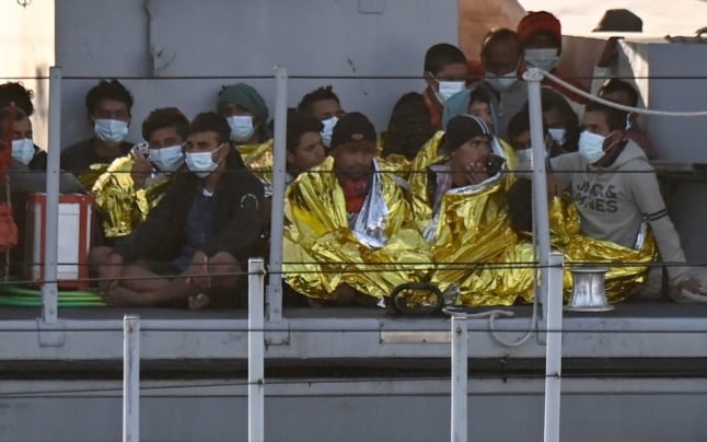 Migrants warmed by emergency blankets arrive on a boat of the Italian Guardia Di Finanza law enforcement agency on May 17, 2021. 
