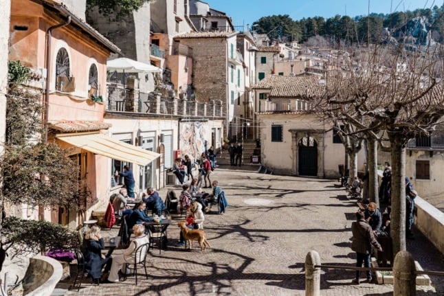 People enjoying coffee in the sun in a piazza outside Rome. 