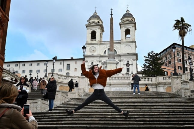 A tourist poses for a picture in front of the Spanish Steps in Rome on March 3, 2020