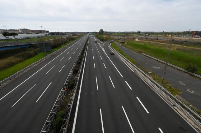 A general view taken from a bridge shows a few cars driving through a deserted highway leading to Rome's Fiumicino international airport 