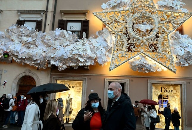 People wear protective face masks on Piazza di Spagna in central Rome on December 05, 2021. 
