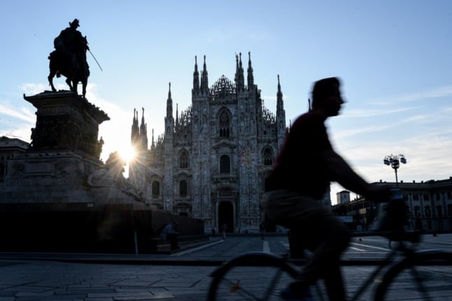 A man cycles past the Duomo Cathedral as the sun rises over Milan on July 16, 2021.