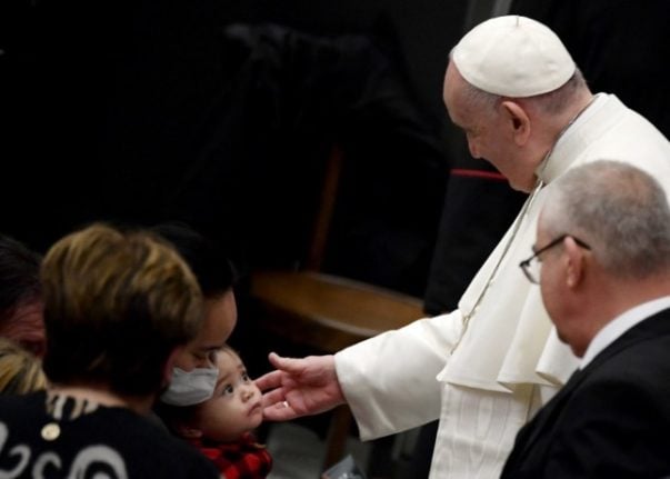 Pope Francis blesses a child during his general audience at the Paul VI Hall at the Vatican on January 5, 2022 (Photo by Filippo MONTEFORTE / AFP)